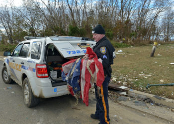Nowojorski policjant sprząta flagi narodowe po uderzeniu Huraganu Sandy (fot. Flicker-Creative Commons)